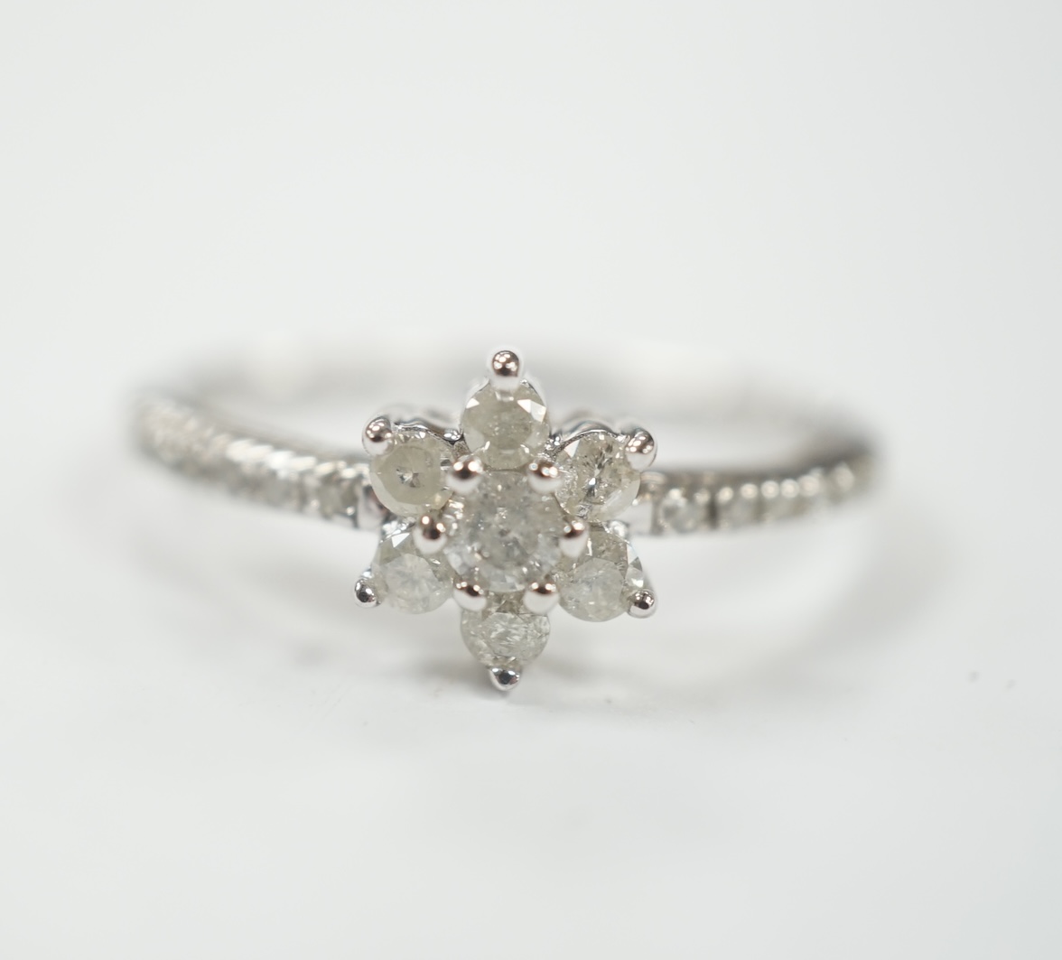 A modern 9ct white gold and diamond cluster set flower head ring, with diamond chip set shoulders, size R/S, gross weight 2.8 grams.